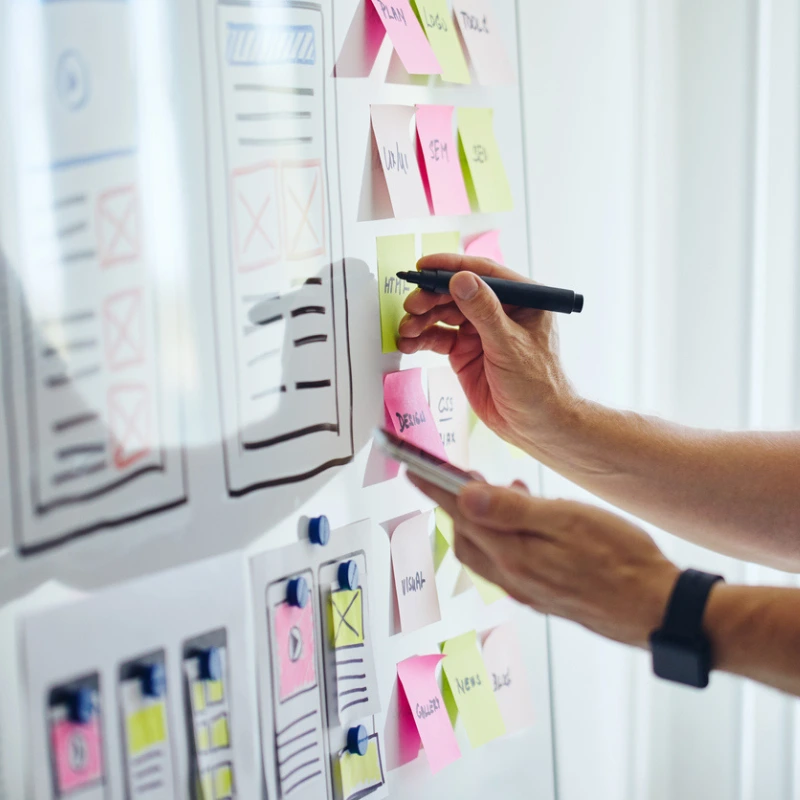 Homme écrivant sur un tableau blanc remplie de post-it