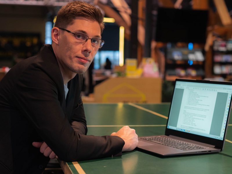 Photo de Matthieu, gérant de Formules 7, accouder à un bureau où se trouve son ordinateur