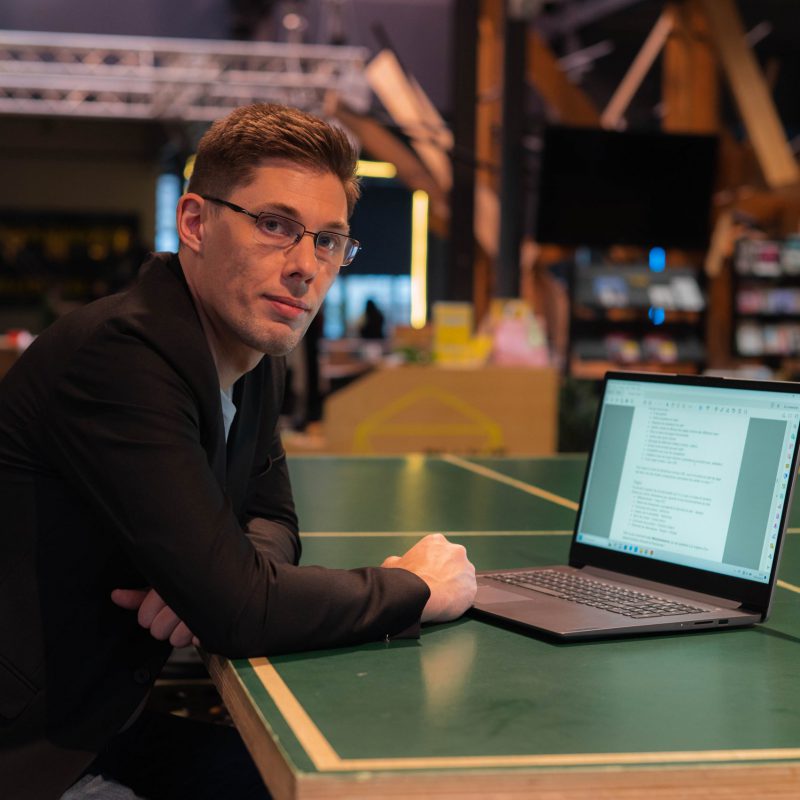 Photo de Matthieu, gérant de Formules 7, accouder à un bureau où se trouve son ordinateur